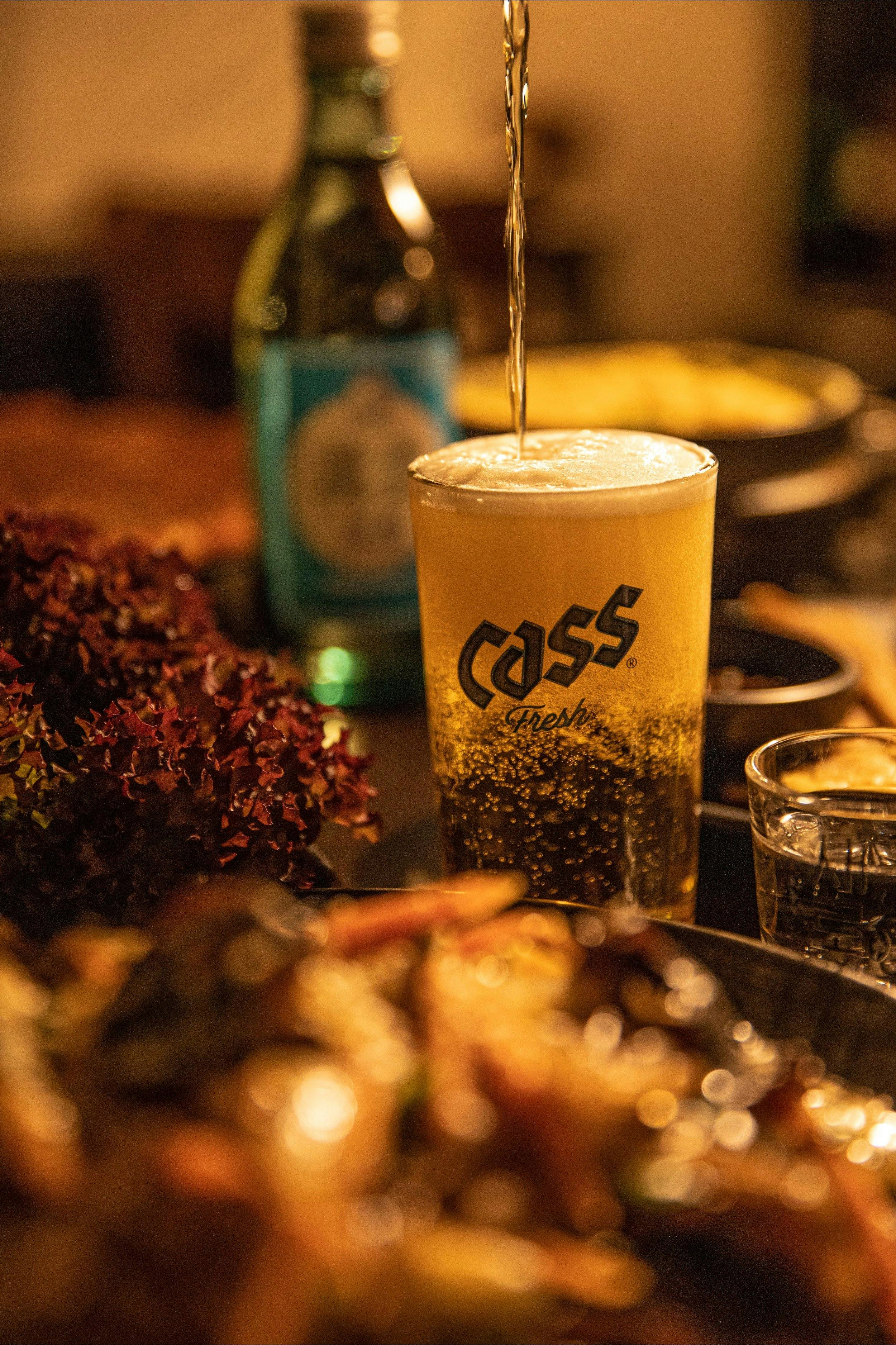 Pouring a Korean beer called Cass into a glass.