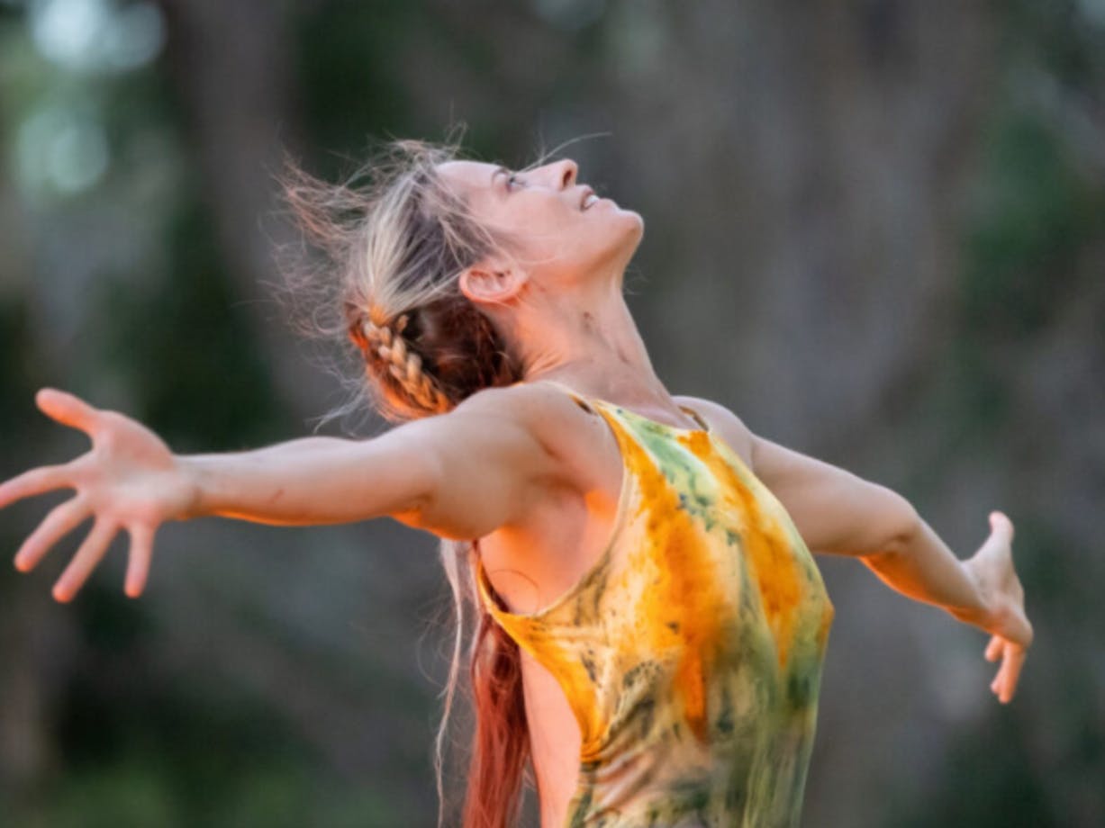 Woman looking up to the sky with her arms spread wide