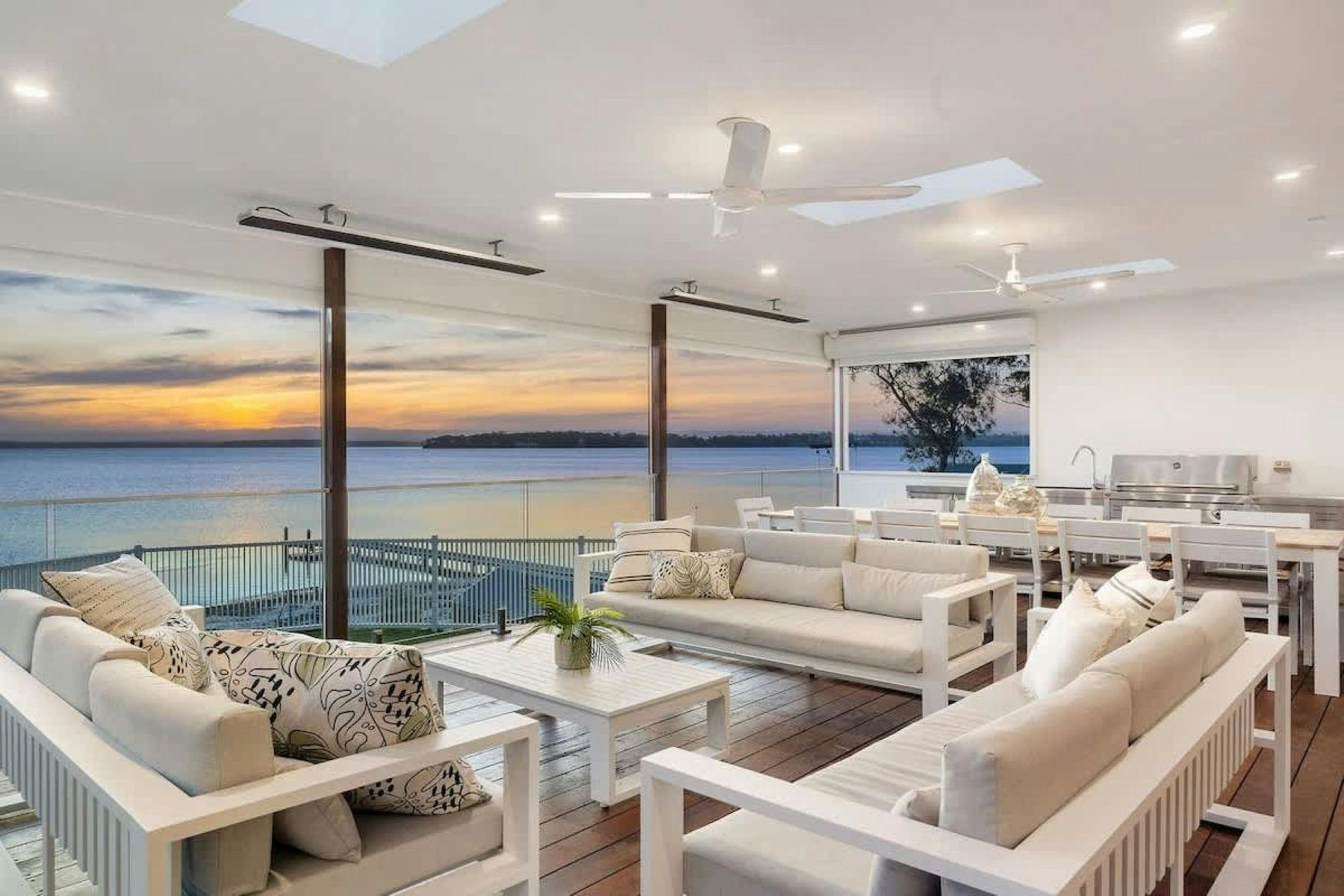 Image of back deck longe area with view of the sun going down over the water