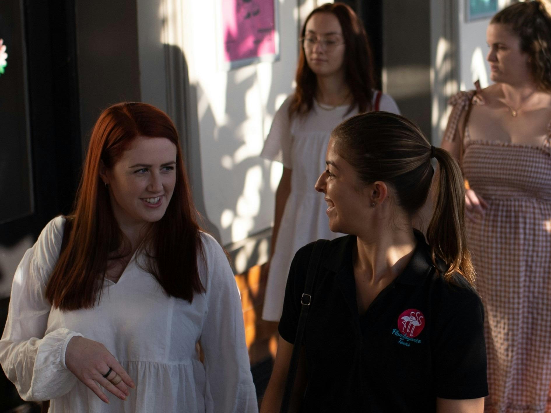 A tour guide and guest chat as they walk down a city street.