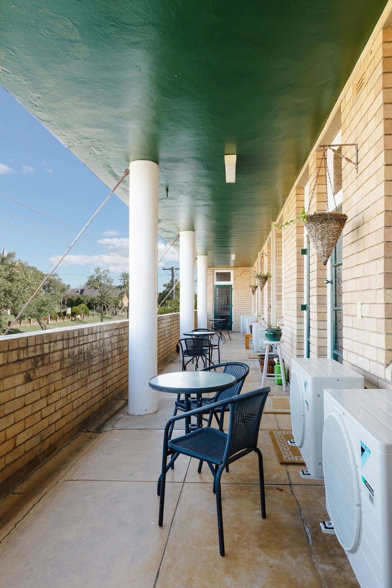 First floor verandah with tables white columns pot plants