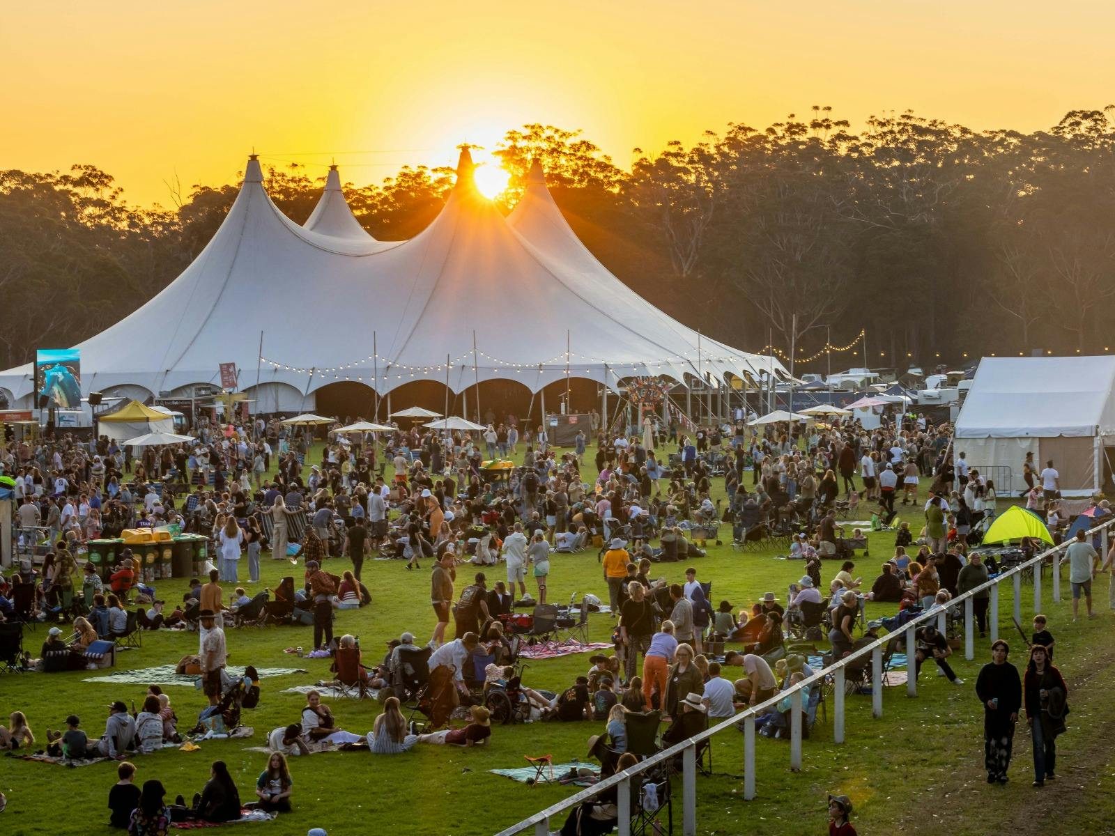 the sun sets behind a big top tent