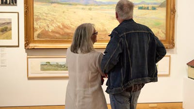 Visitors observing a landscape painting in the Canberra/Kamberri exhibition