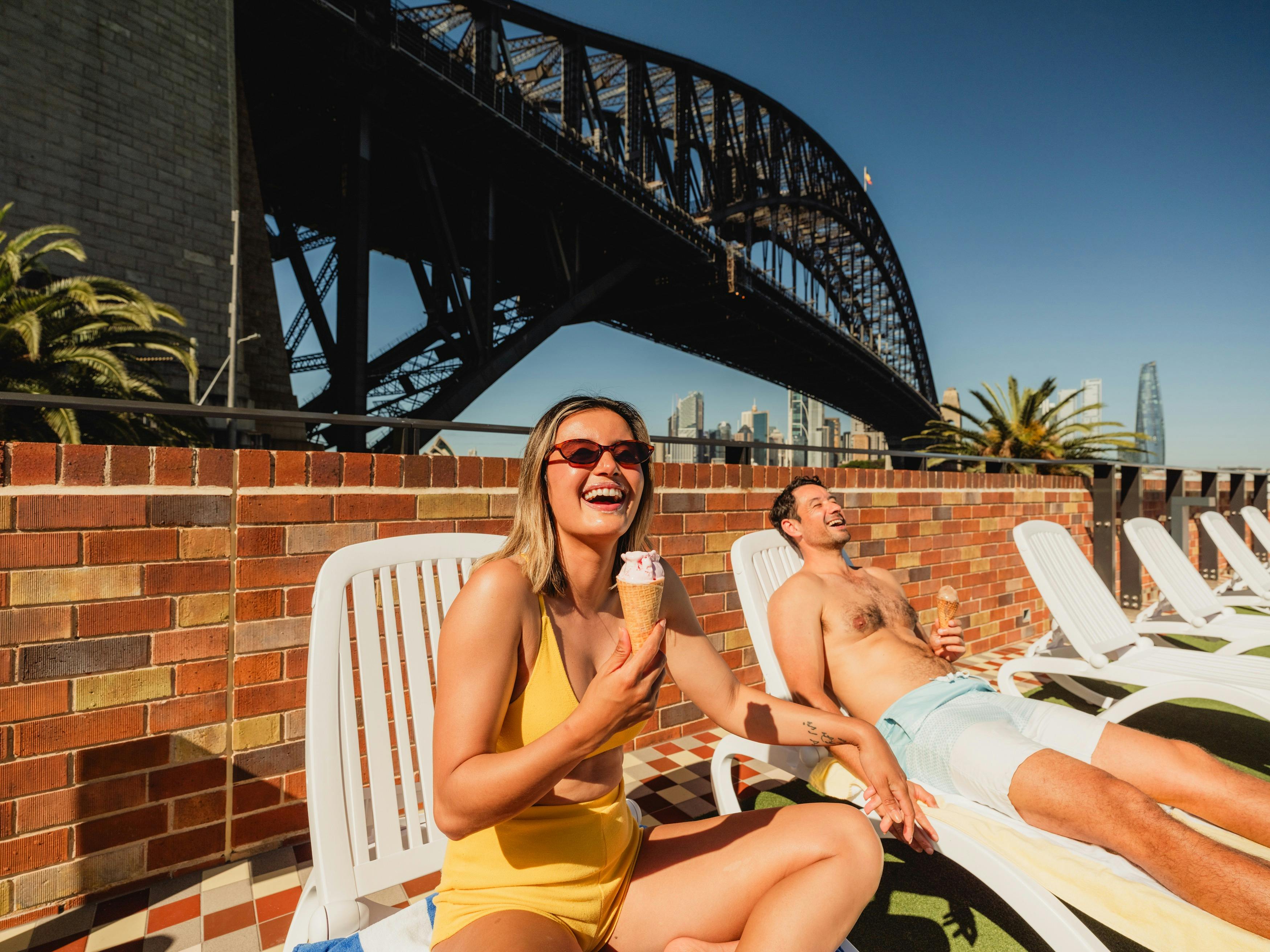 People on sunbeds eating icecream with harbour bridge in background