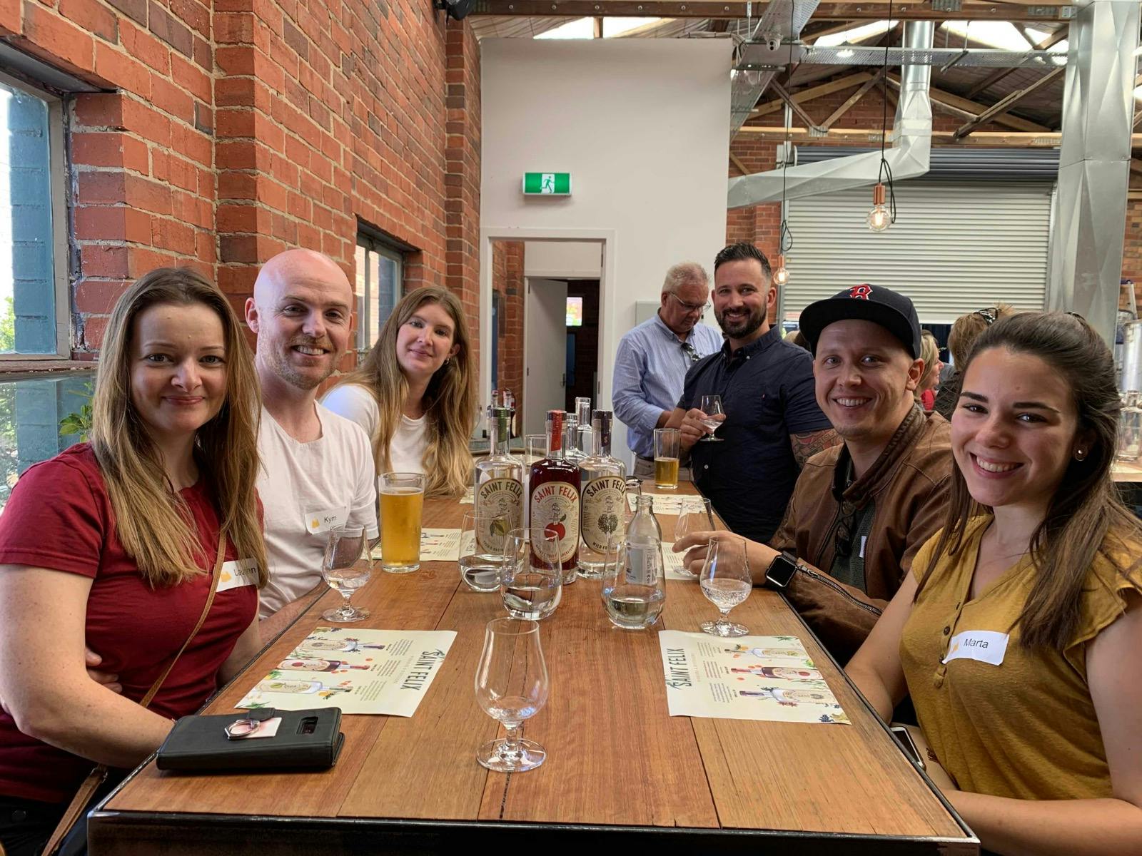 A group of friends at Saint Felix smiling at the camera with three gin bottles in front of them