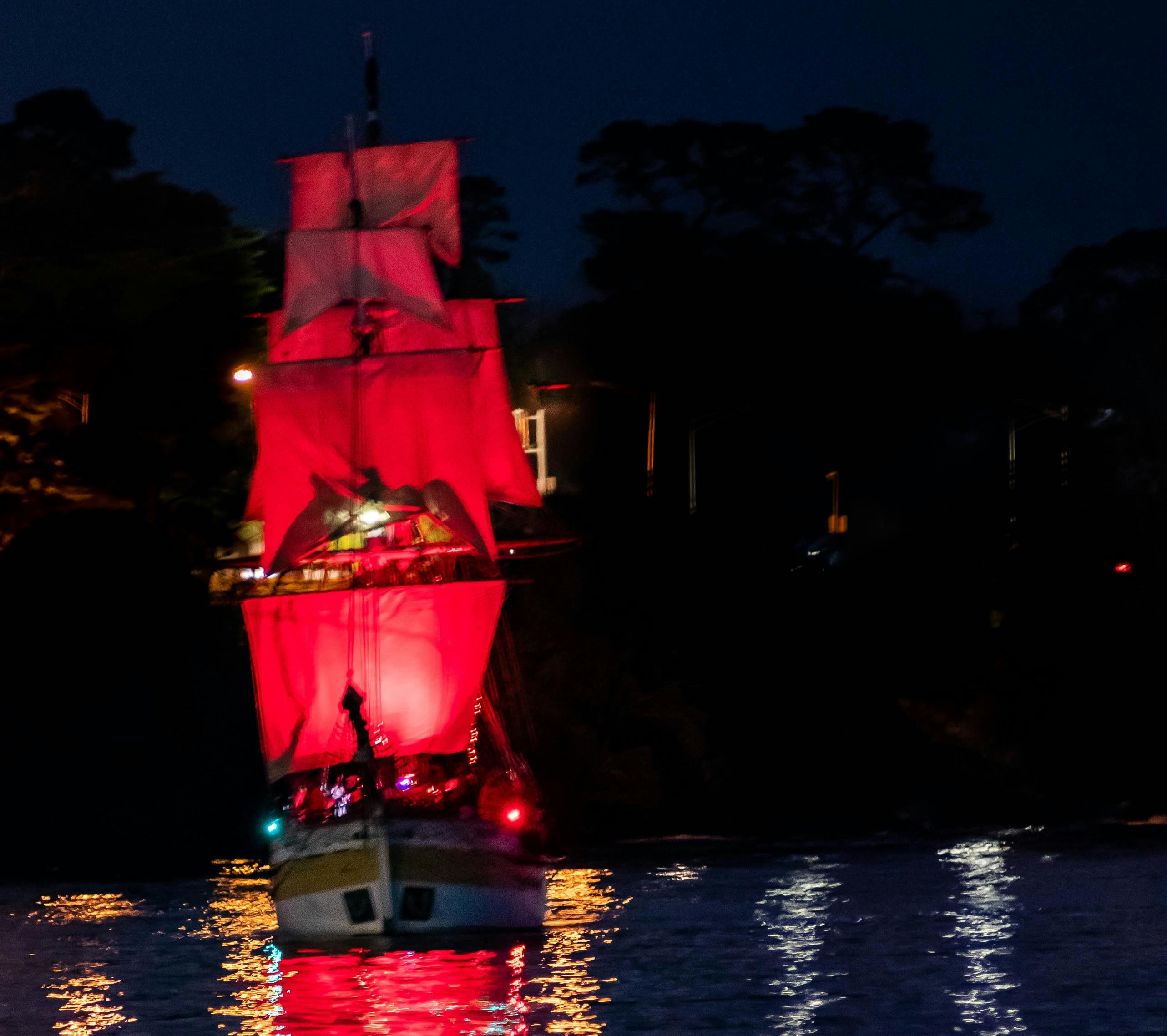 Lady Nelson sailing with red lit up sails