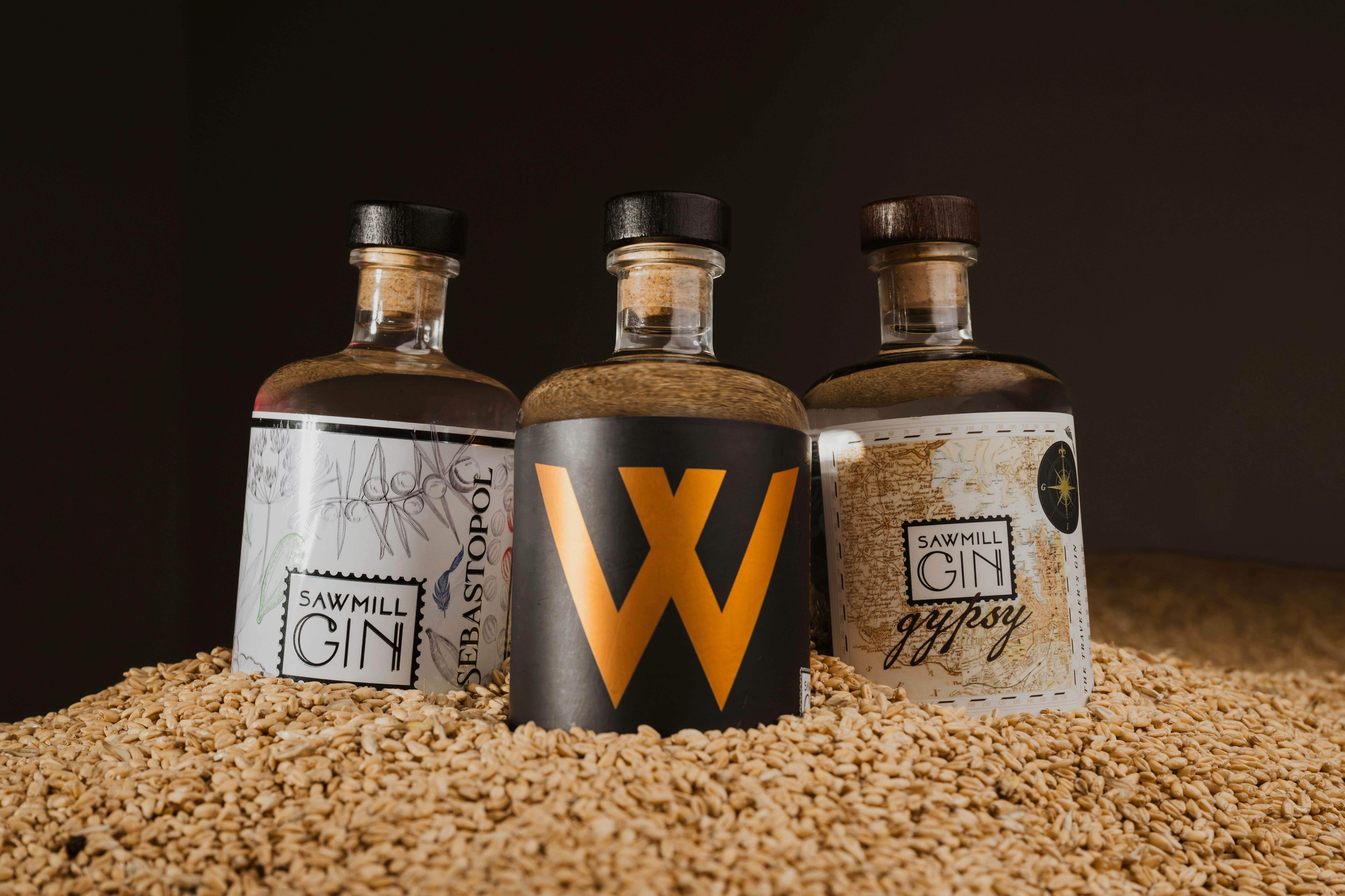 Three Gin bottles nesting in wheat grains with a black background