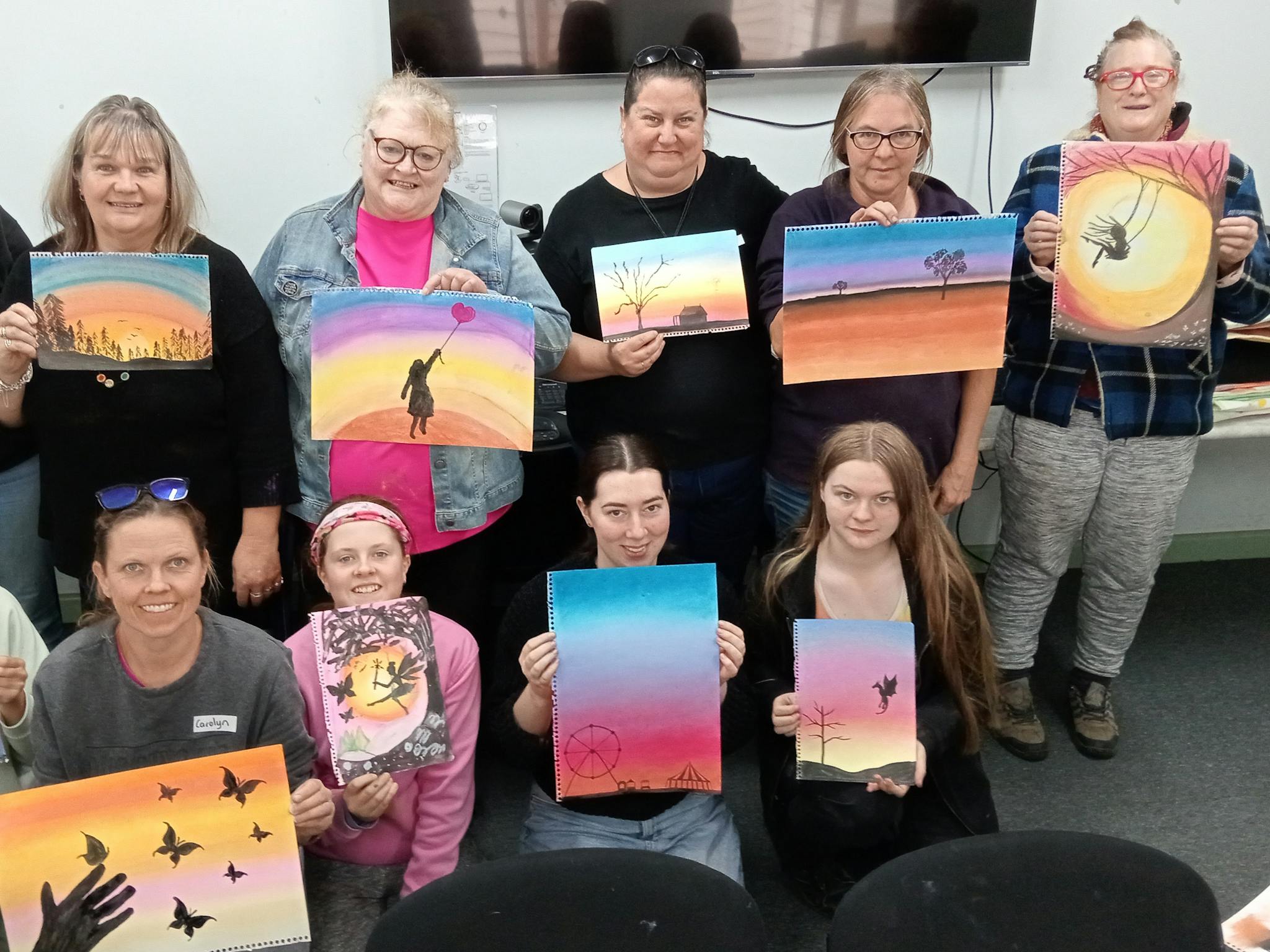 Pastel Art Class at Pax Art Studio ladies holding colourful artworks of sunsets