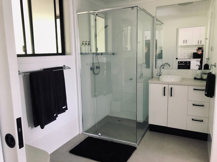 white tiled bathroom with glass shower and vanity