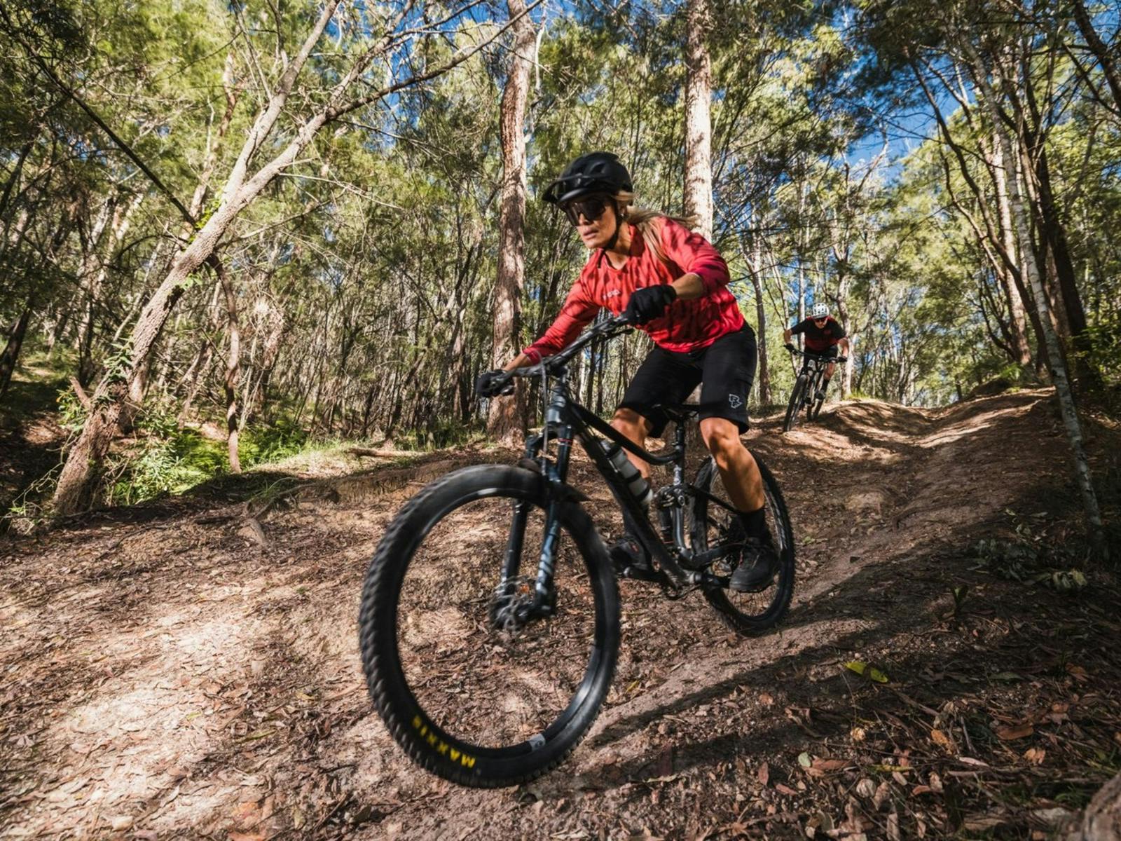 Couple riding mountain bikes and enjoying trails at Redlands Track Park, QLD. Couple riding mountain bikes and enjoying trails at Redlands Track Park, QLD.