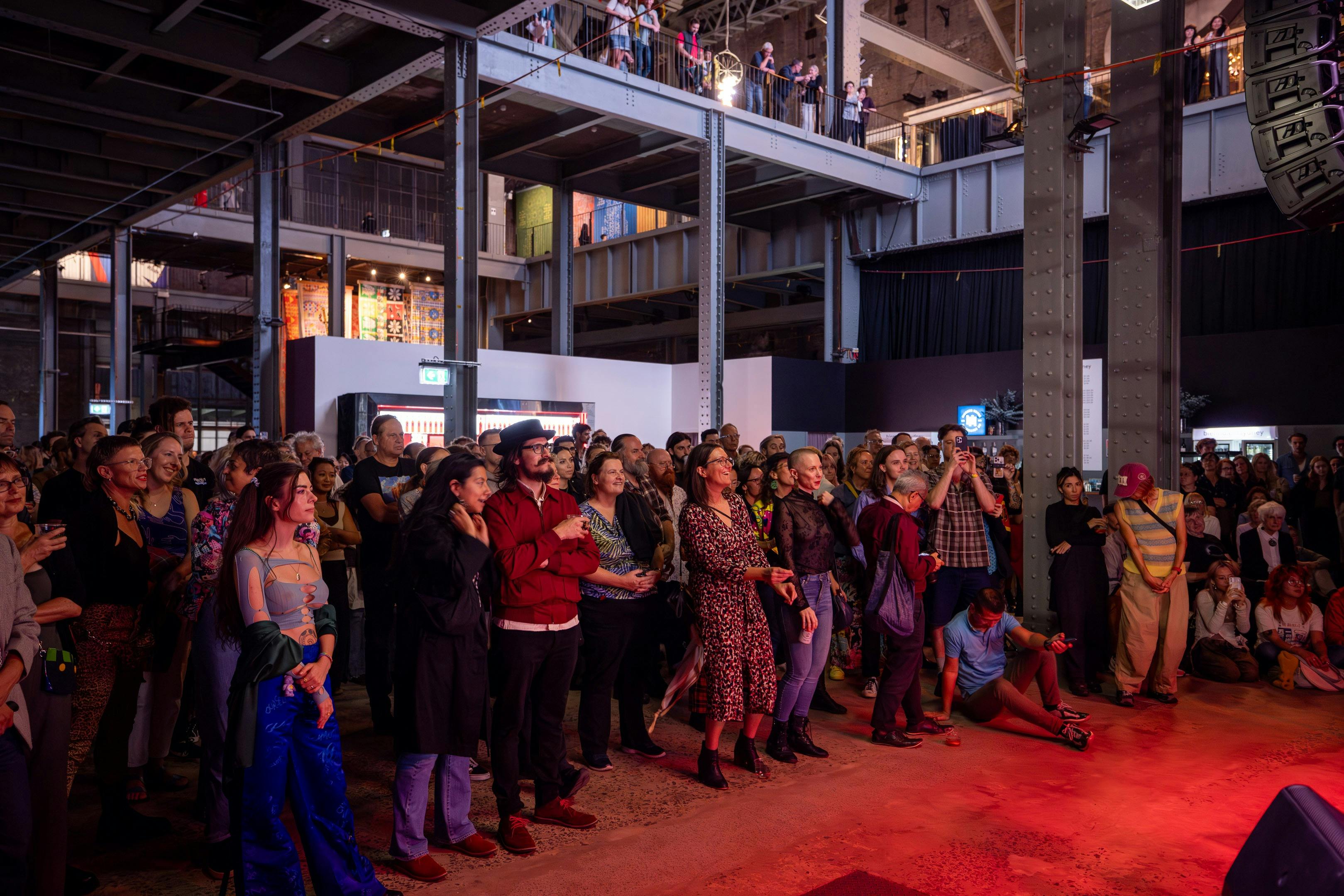 crowd of people in the boiler house of a power station, looking toward the stage with a musician