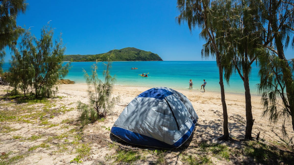 View from Steens beach of tent with people on beach and people kayaking in distance