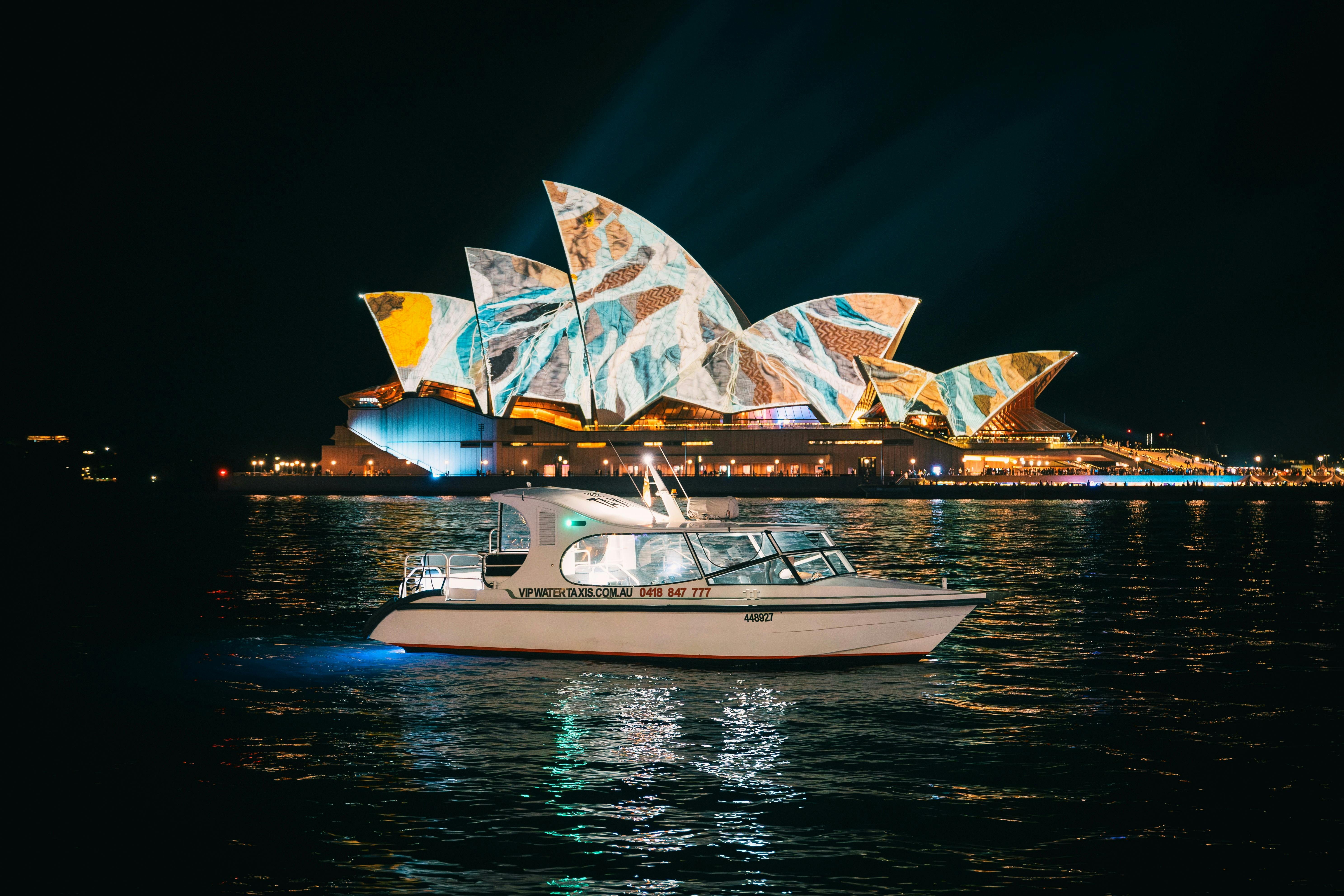 Water taxi on Sydney Harbour with the Opera House illumanted behind with art