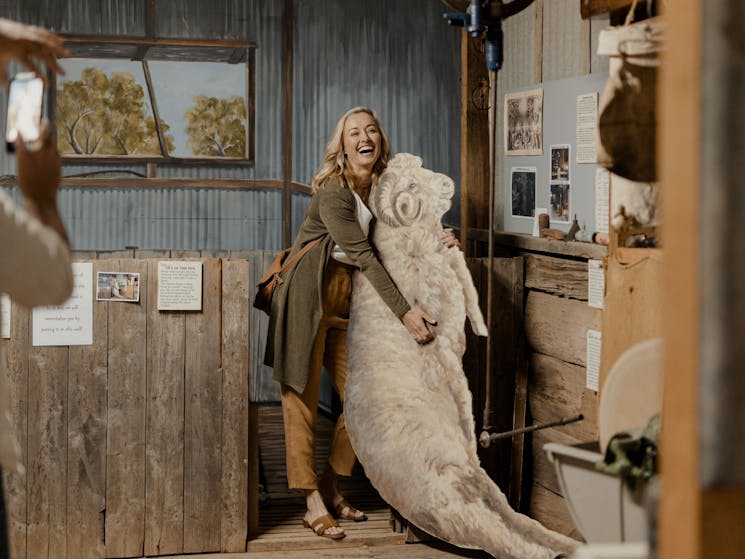 Lady holding cardboard cutout of ram in th recreation of the Shearing the rams display