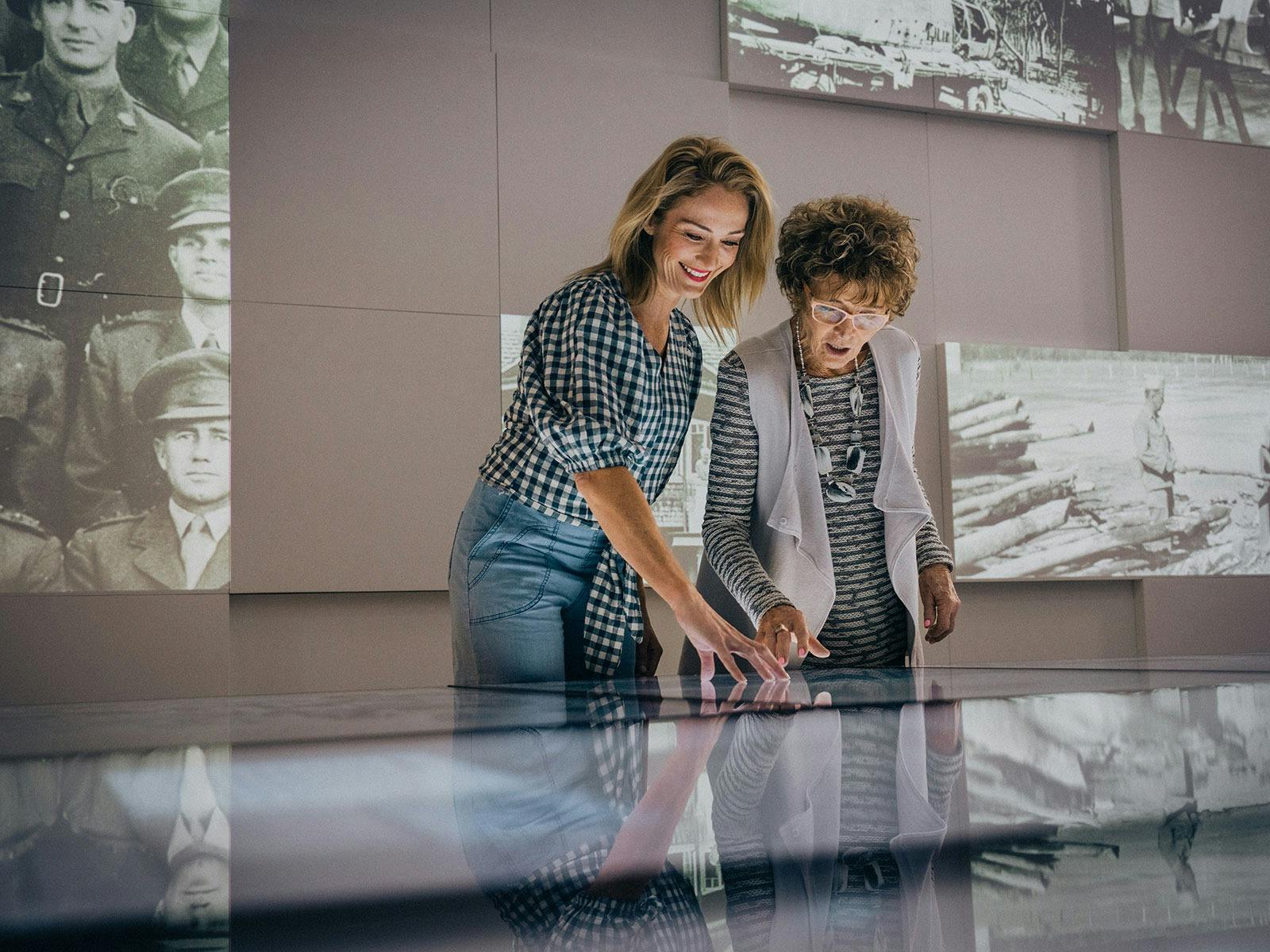 Mother and daughter using the interactive screens inside Anzac Square Memorial Galleries