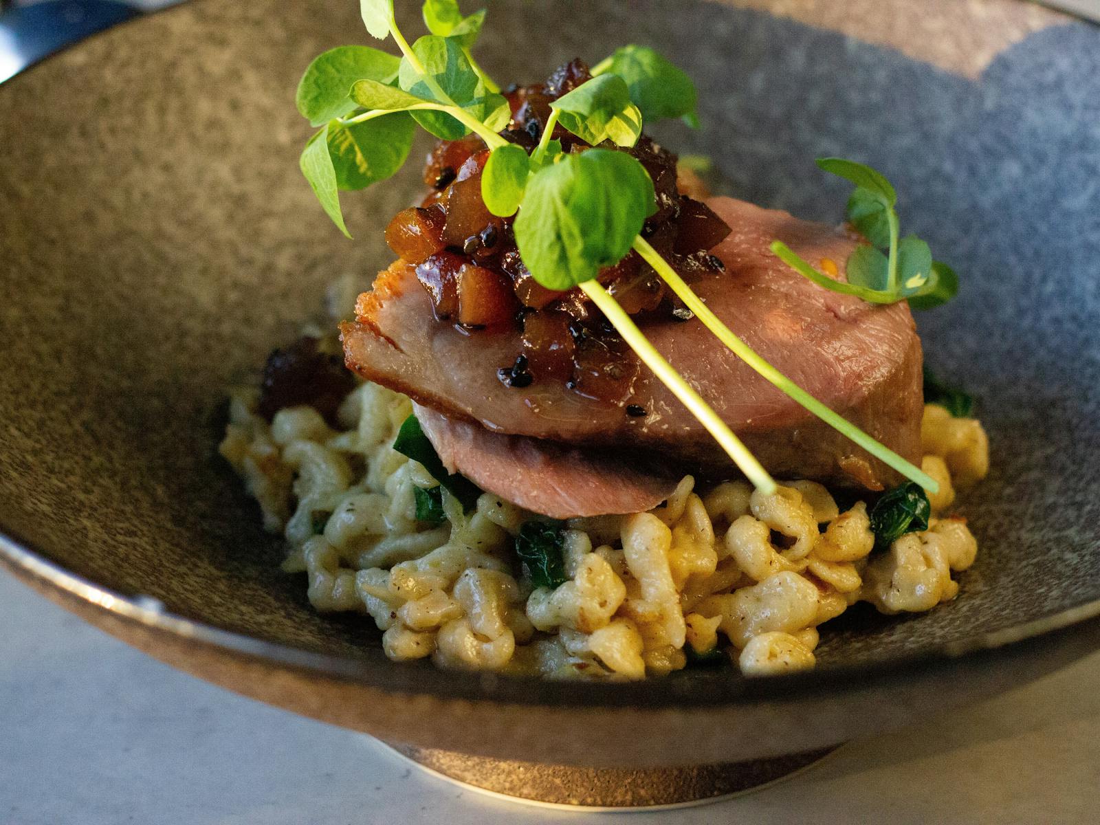 Close up image of main dinner meal of duck breast with spinach a spatzle.