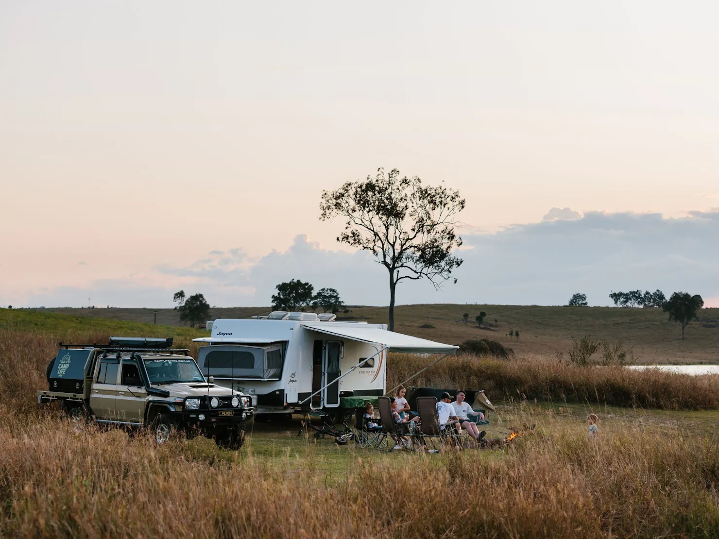 A family sitting in front of their caravan