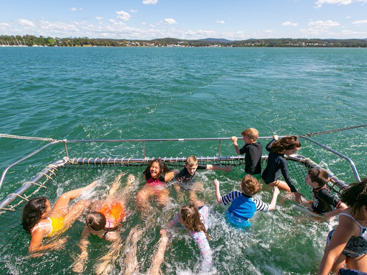 Kids playing in the boom net off the back of the vessel Lady Mac