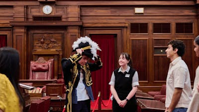 MoAD Experience Officer with group of people in the Senate Chamber