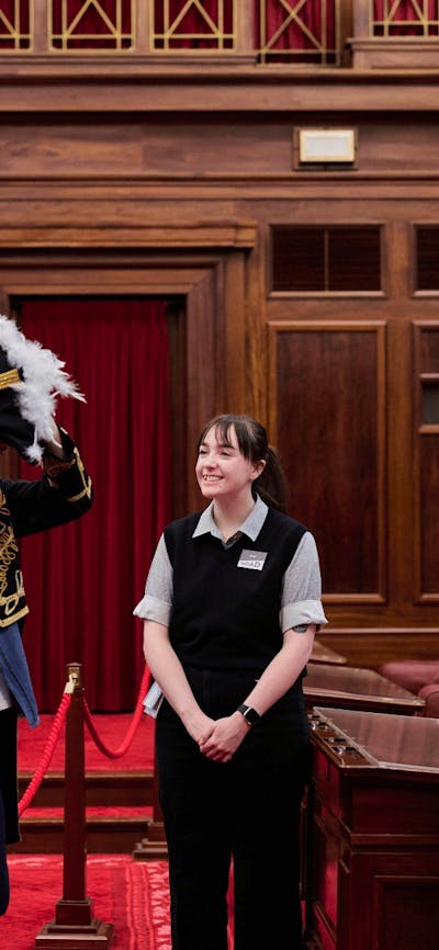 MoAD Experience Officer with group of people in the Senate Chamber