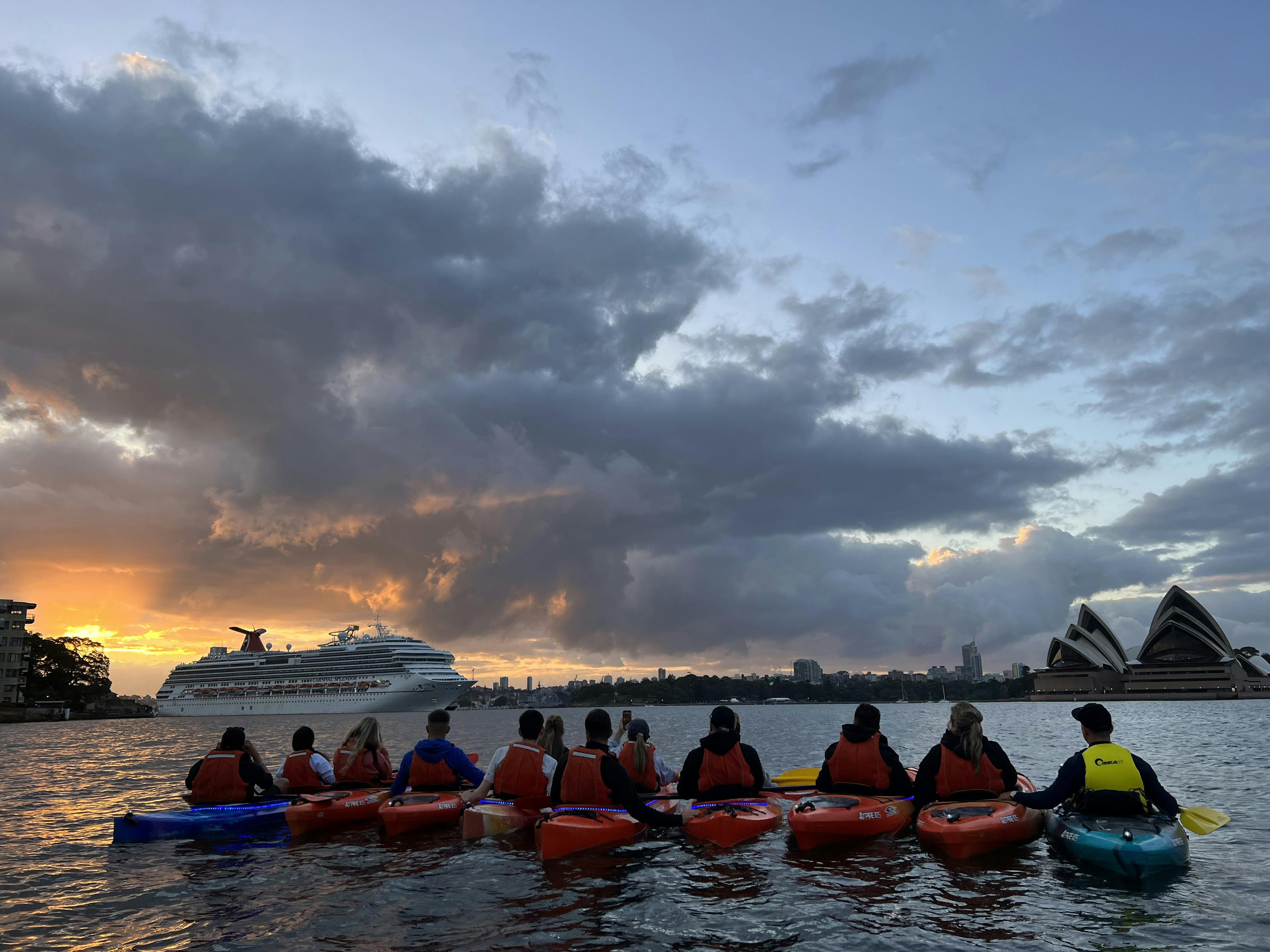 a team of kayakers line up to see the sun rise in Sydney Harbour