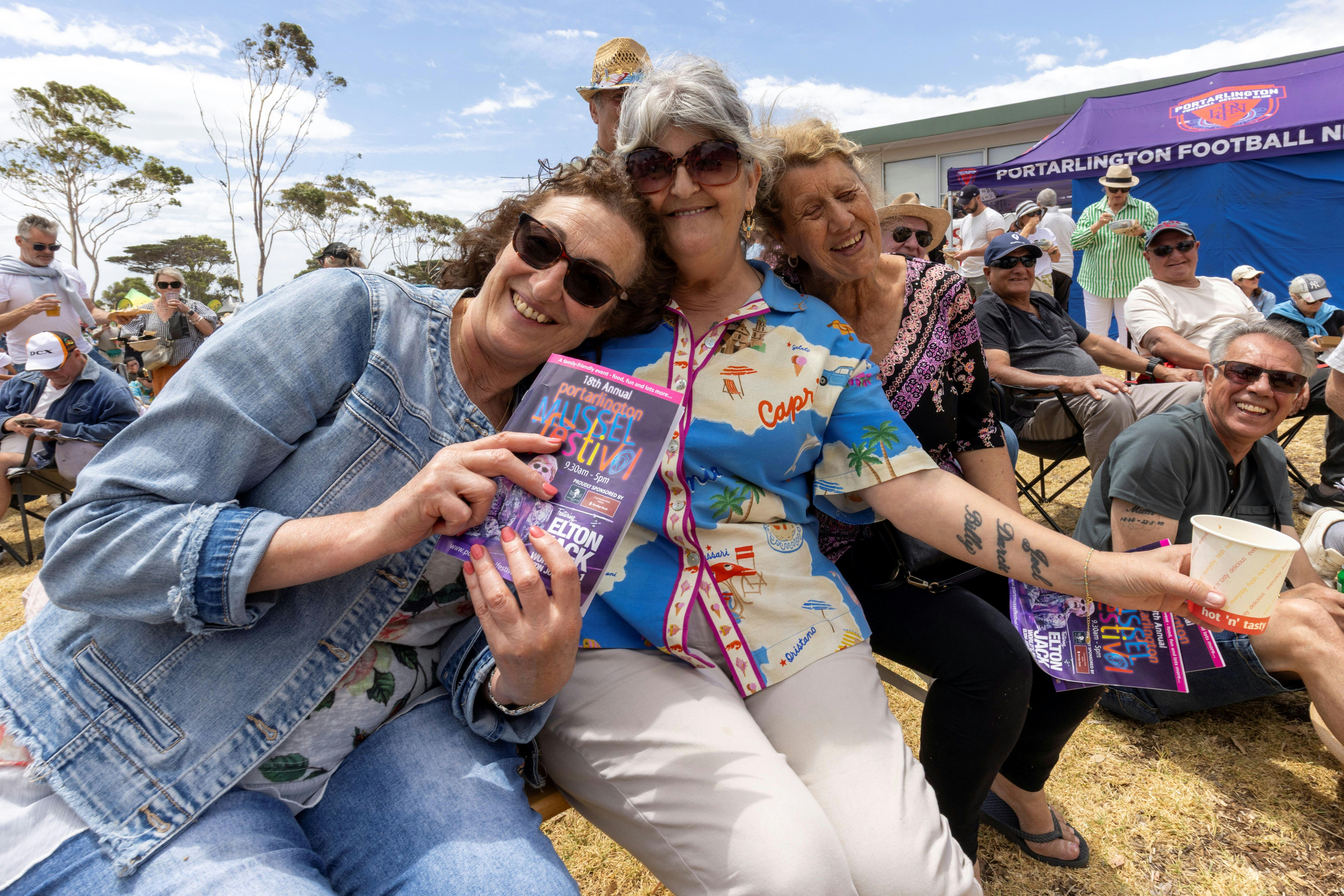 3 people having fun and smiling at the camera with a Portarlington Mussel Festival program