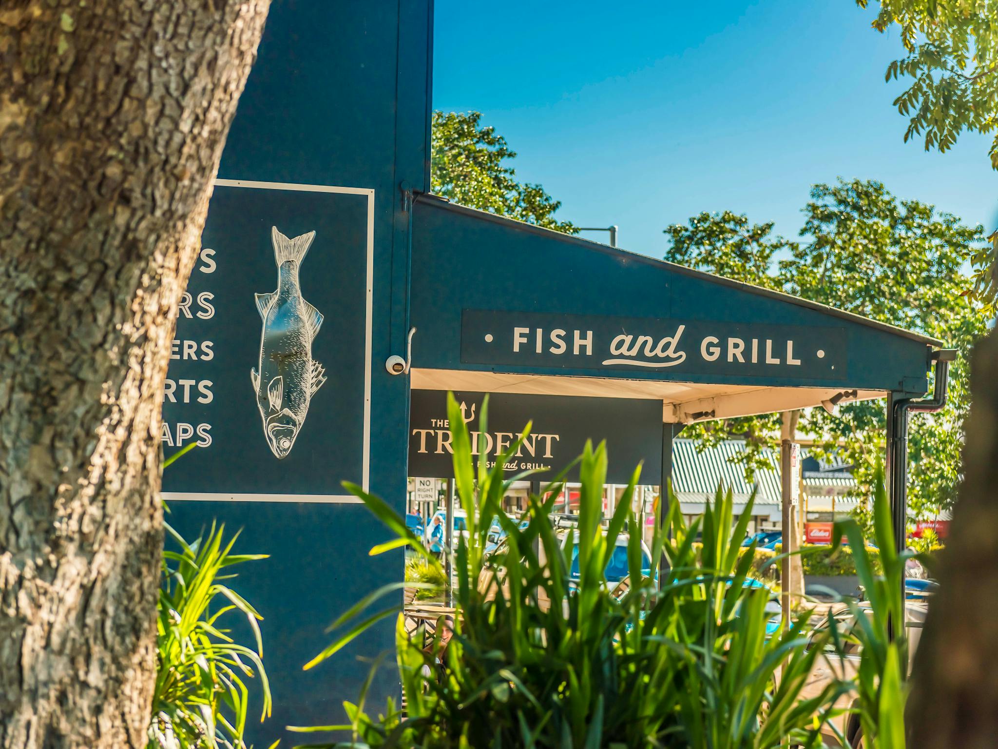 Image of an navy blue fish and chip shop exterior with trees nearby