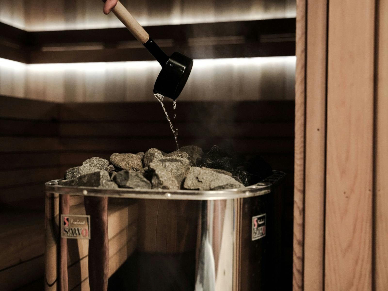 Water gently being poured over hot rocks in a steam sauna