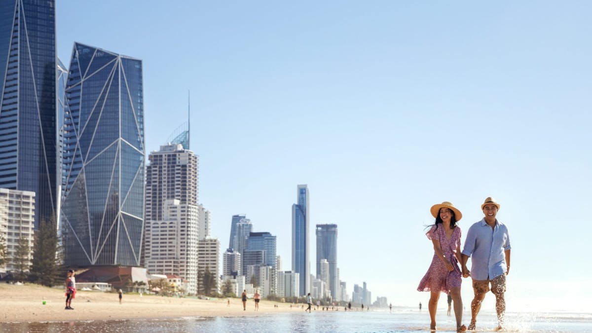 A couple strolling along the beach near a high-rise city skyline
