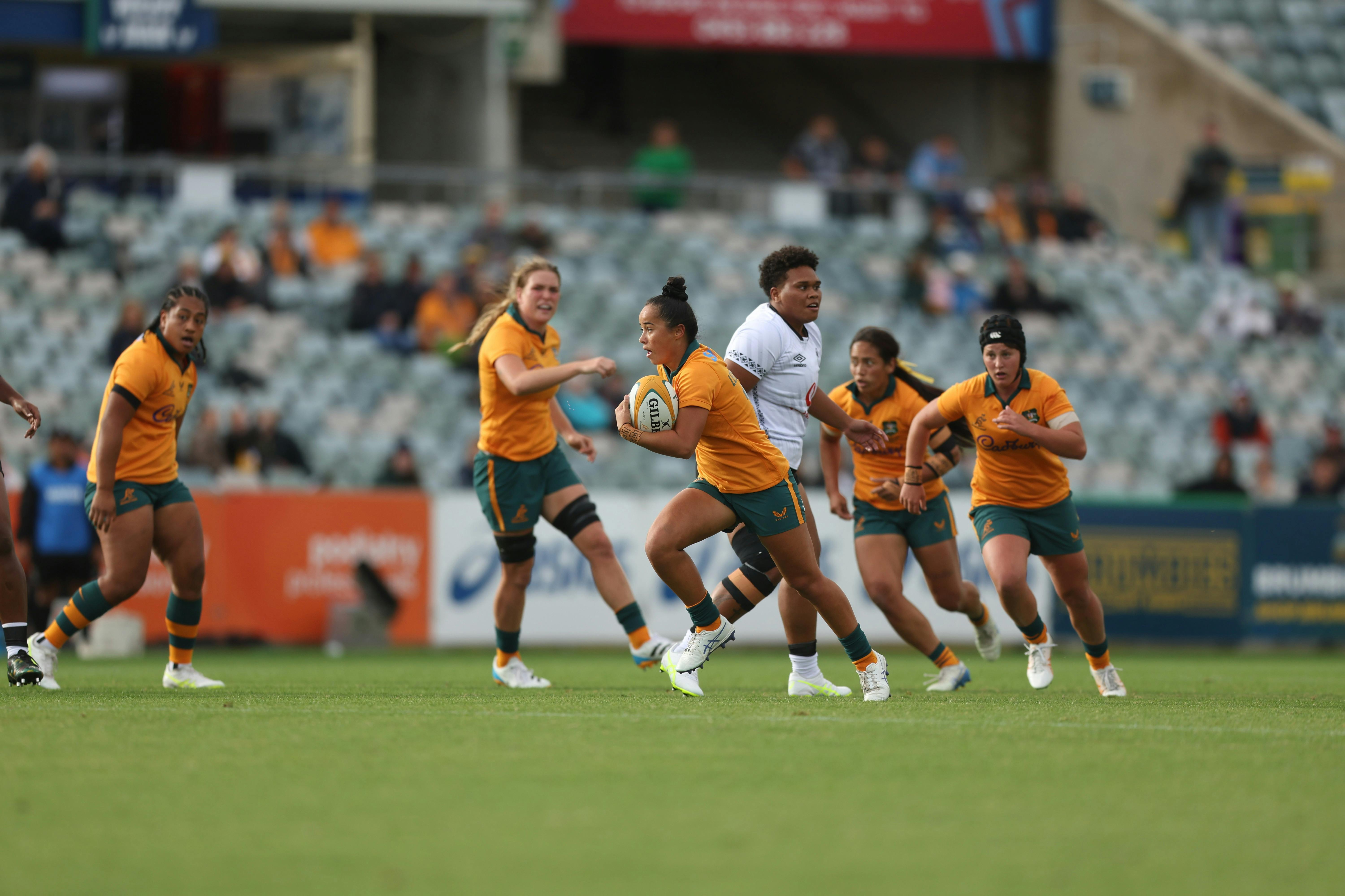 Rugby player running with ball in hand while team mates watch