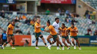 Rugby player running with ball in hand while team mates watch