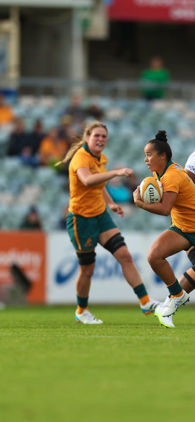 Rugby player running with ball in hand while team mates watch