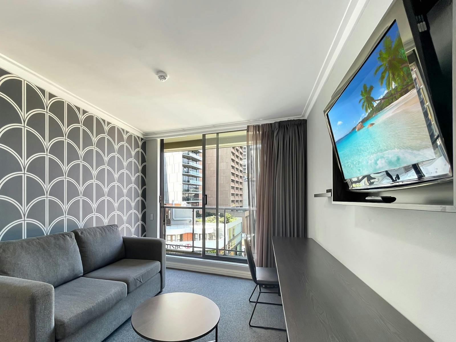 Living room with wall-mounted TV, sofa seating, and city outlook.