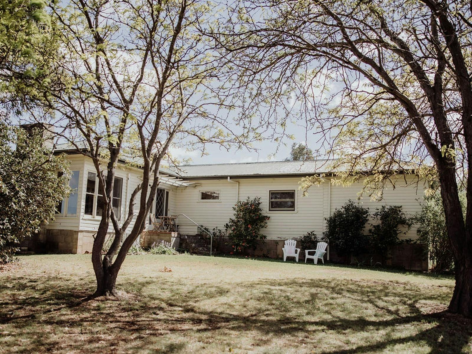 White weatherboard  cottage near Rylstone, surrounded by established trees and garden