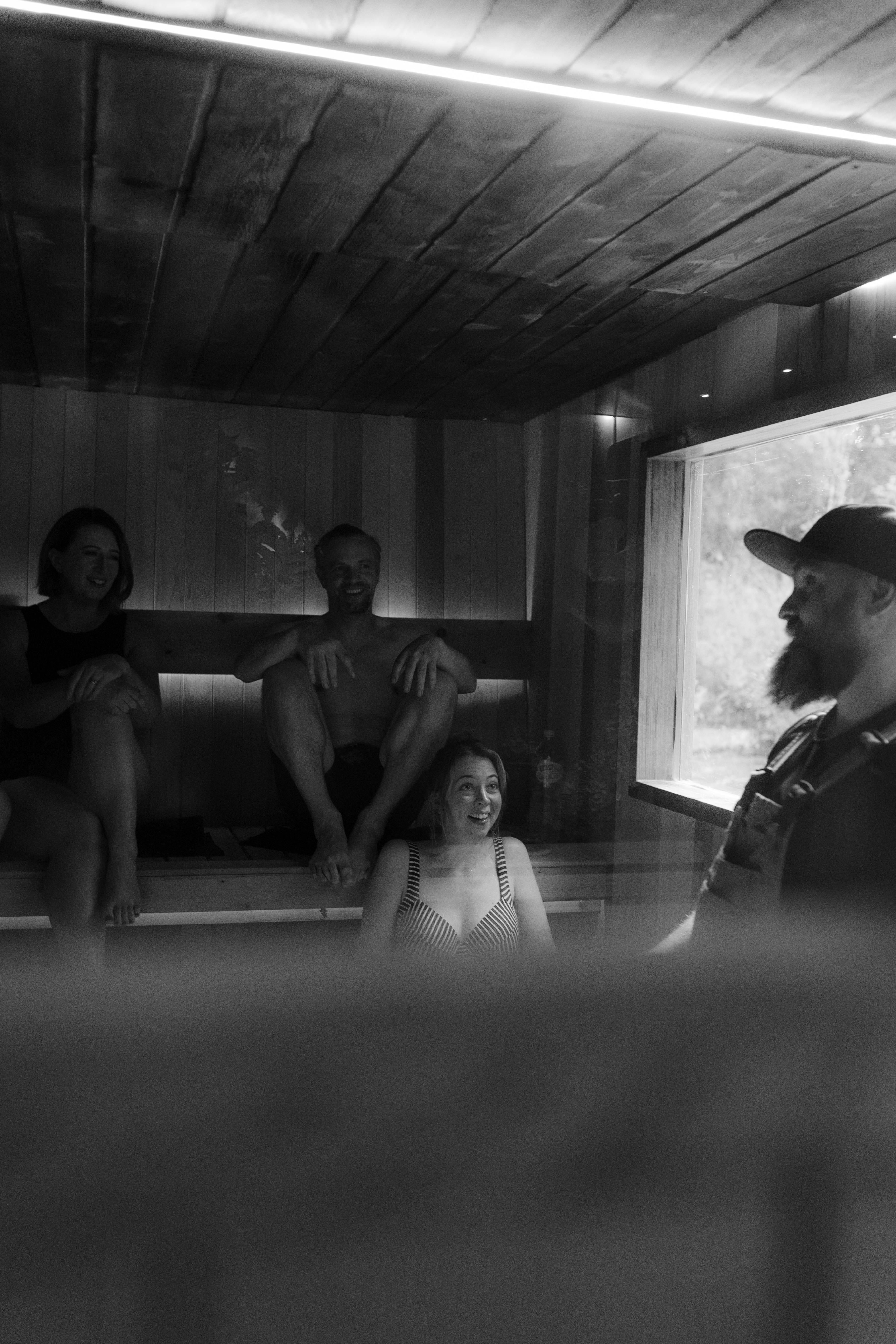 Guests listening to a guided sauna session inside a warm timber-lined wood-fired sauna.