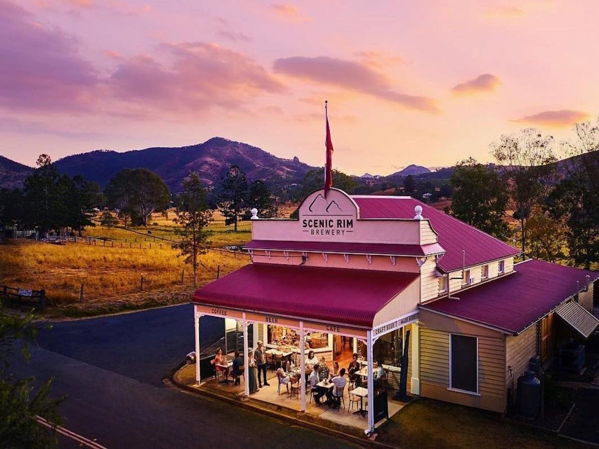 A small historic building set among fields with a mountain range behind