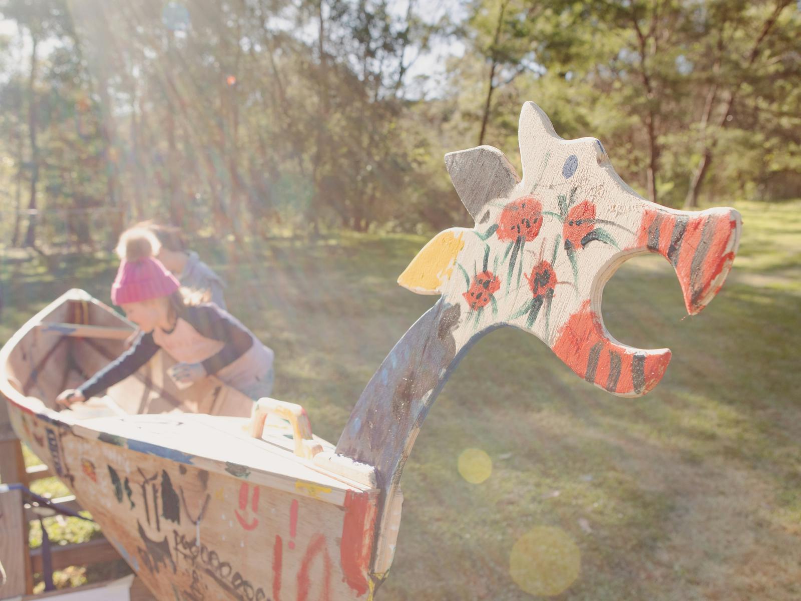 A canoe with a dragon head that has been painted by kids
