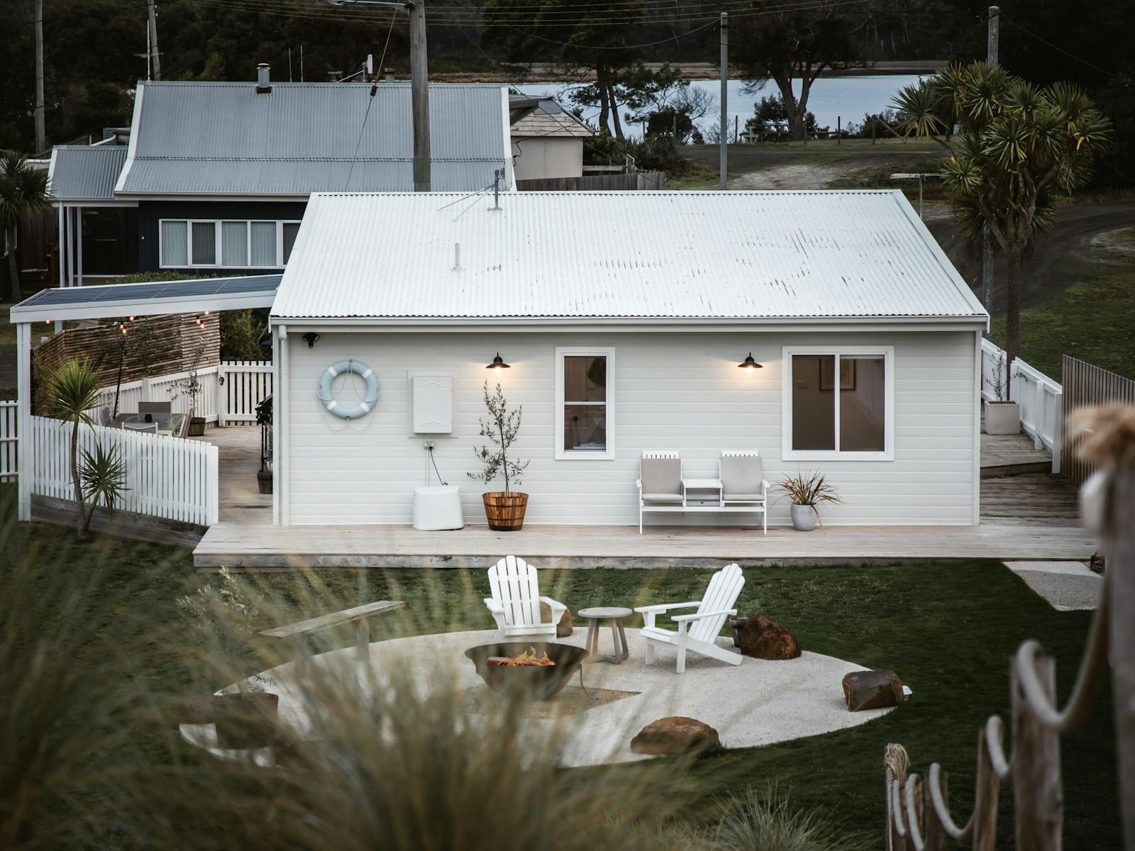 A white beach cottage with firepit and al fresco seating