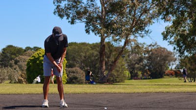Male golfer making a putt on sand greens