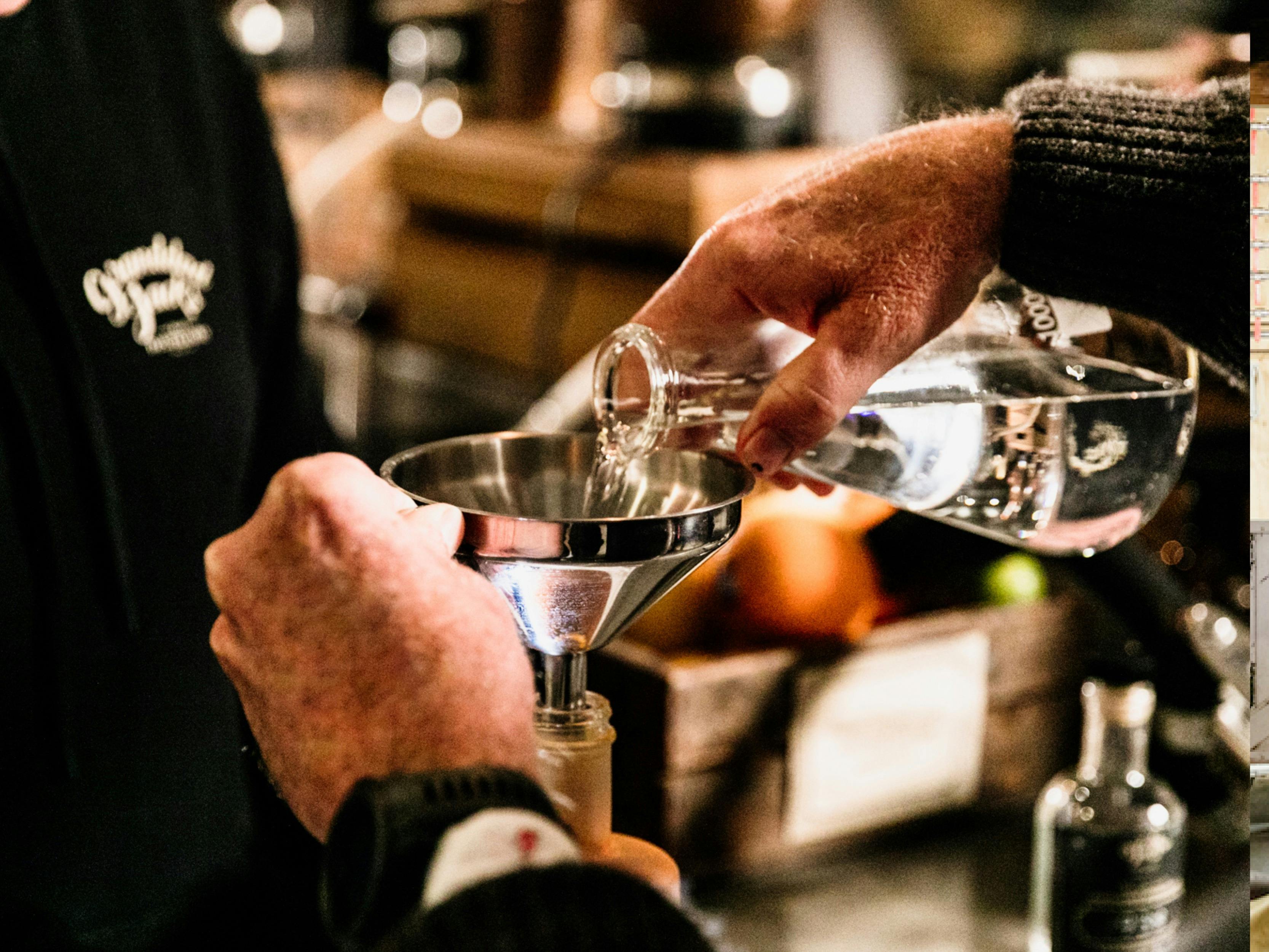 A guest pouring their gin into a funnel for measurement.