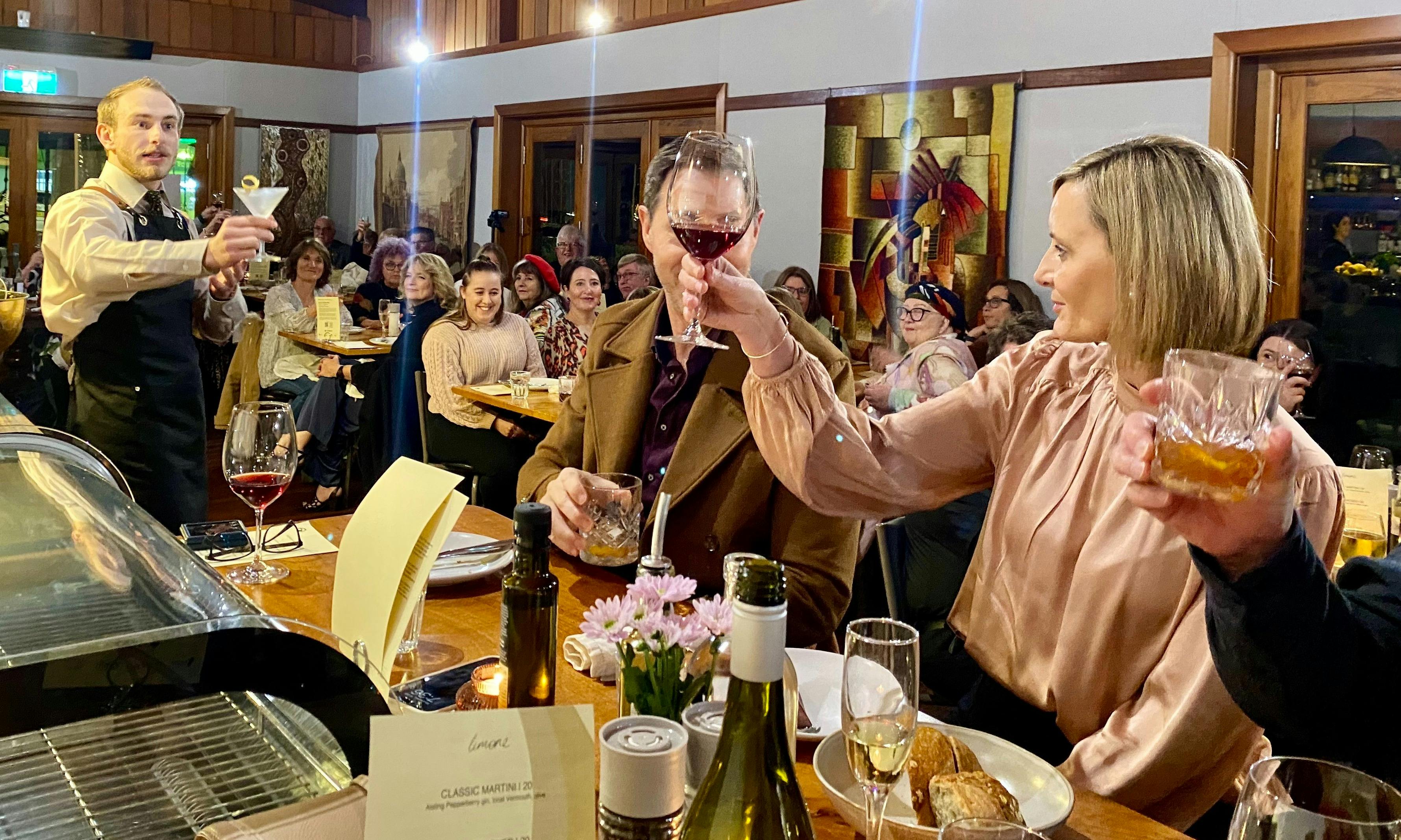 Audience member raises her glass, sharing a toast with the performing bartender