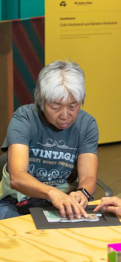 A photograph of 2 participants of Art by Description and a staff member using tactile resources