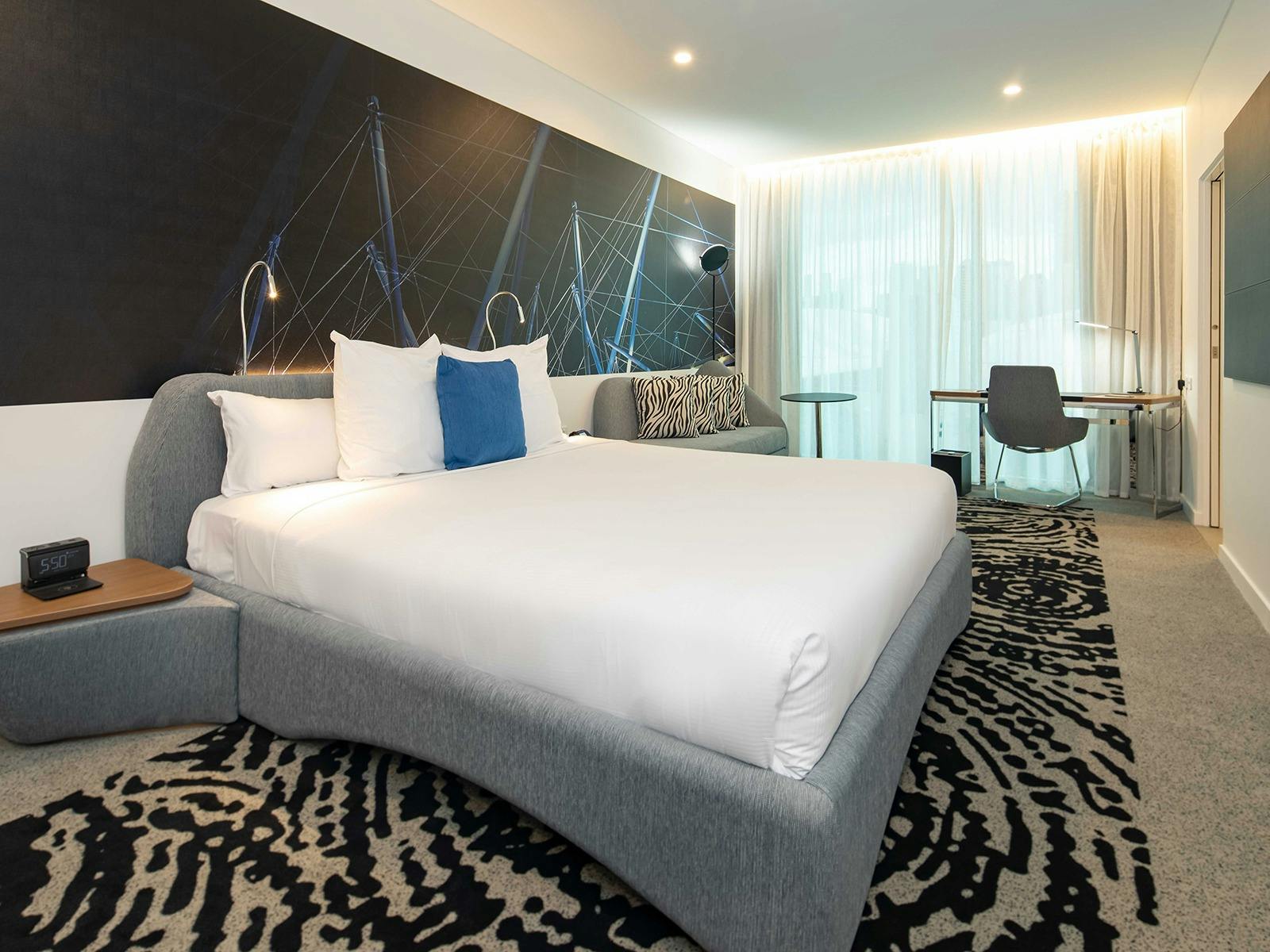 Room with king bed with white bed sheets and working desk close to the windown Room with king bed with white bed sheets and working desk close to the windown