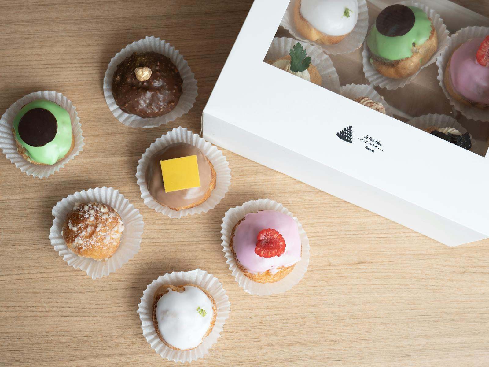 French chou pastries of different colours in a box, and some outside of a box.