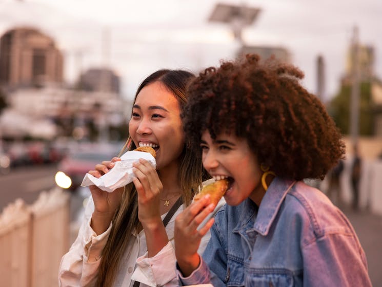 Friends enjoying takeaway food and drink in Little India in Harris Park