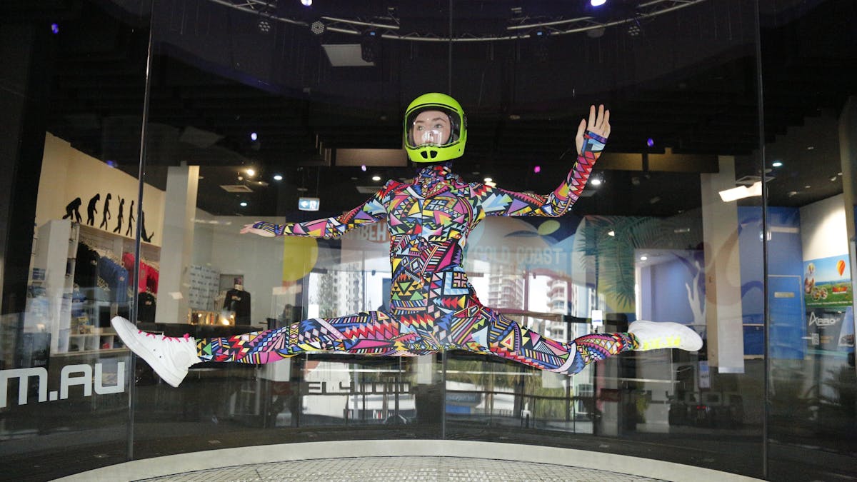 Freestyle flying by experienced junior flyer in colourful suit, performing the splits mid-air.
