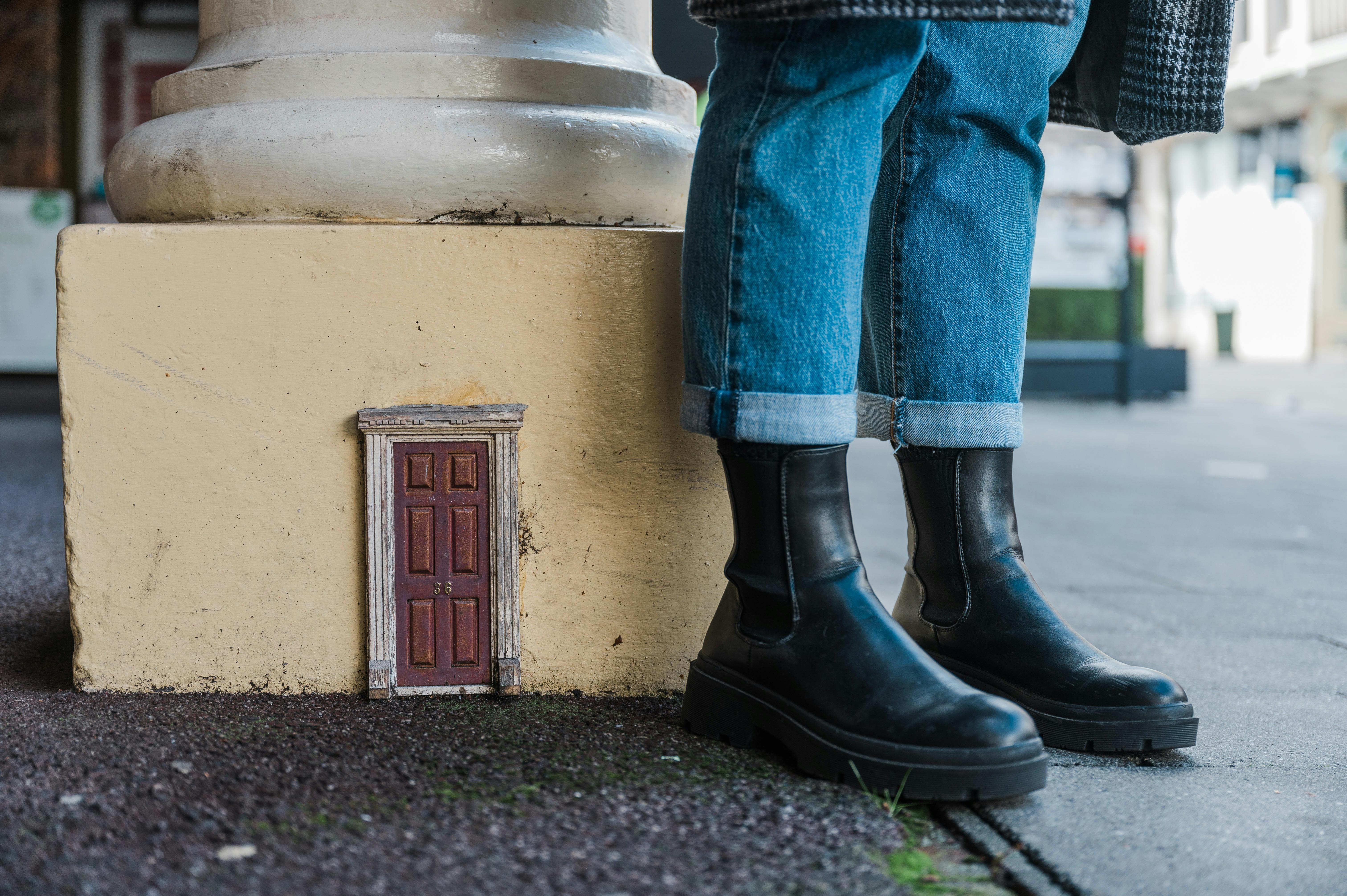 Two feet stand next to a tiny door