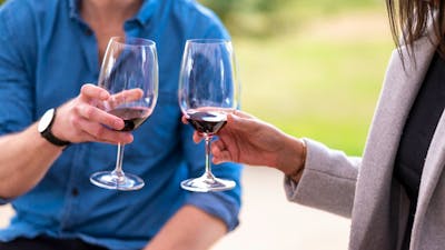 A couple are about to cheers red wine glasses on a wine tasting in Canberra