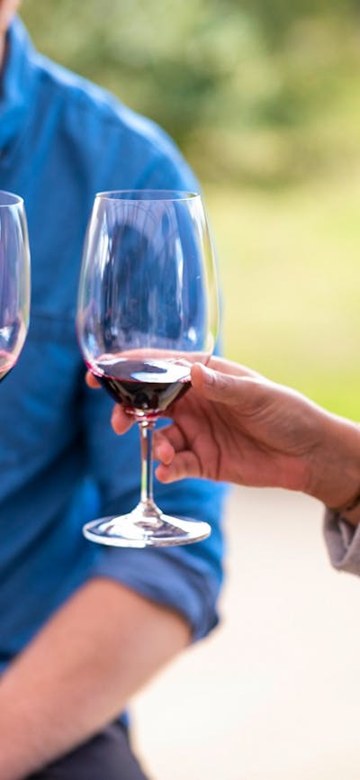 A couple are about to cheers red wine glasses on a wine tasting in Canberra