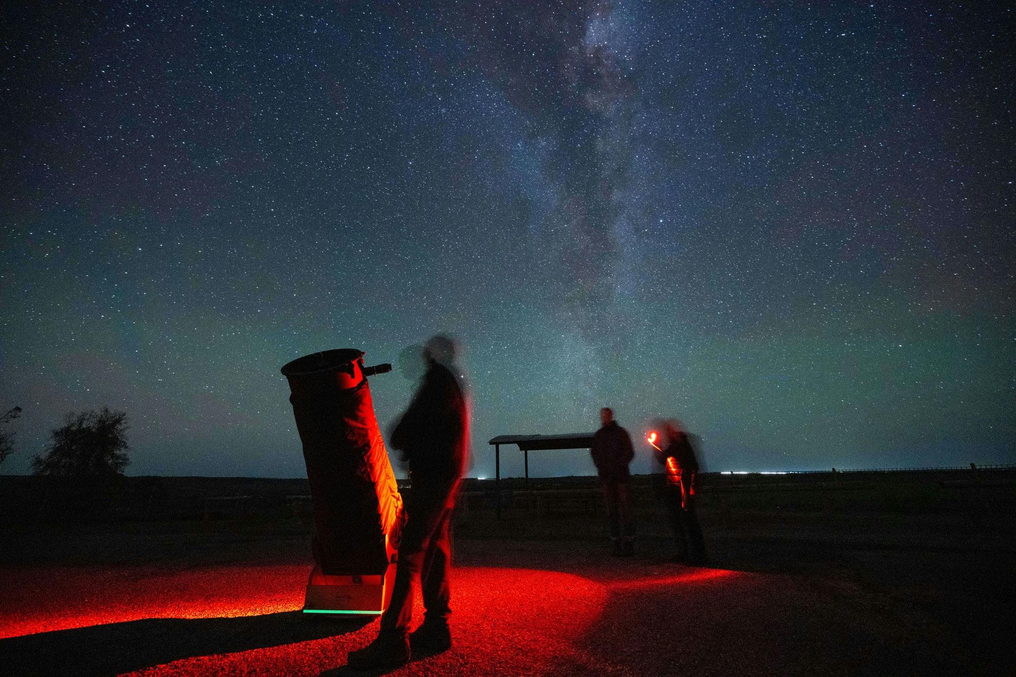 People looking through telescope at Milky Way overhead